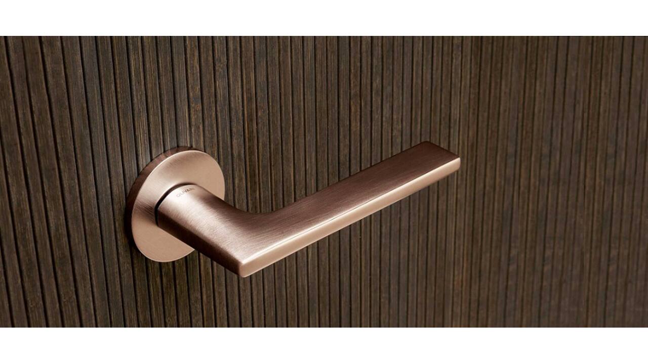 Olivari deurkruk Link + ronde geveerde rozet 51x5mm met nokken en doorgaande bevestiging Koper mat titaan PVD
